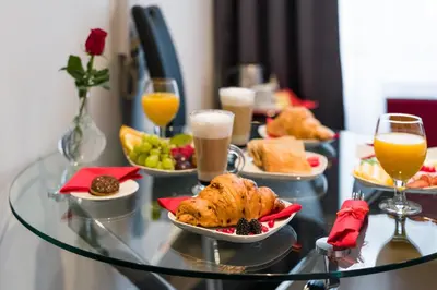 a table topped with plates of food and glasses of orange juice at Komorowski Luxury Guest Rooms in Kraków