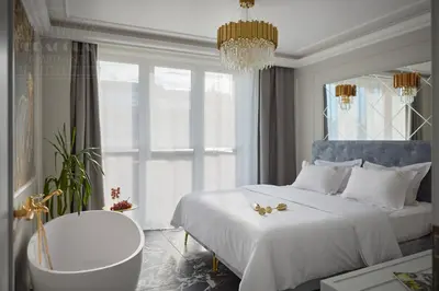 a bedroom with a bed and a chair and a chandelier at Feniks Fragola Apartments in Kraków