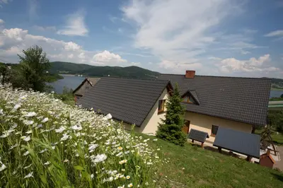 a house with two benches and a field of flowers at Nad Zalewem in Jaszczurowa