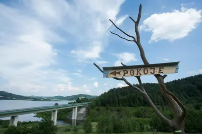 a sign hanging from a tree next to a bridge at Nad Zalewem in Jaszczurowa