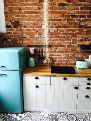 a kitchen with a brick wall and a refrigerator at Przestrzenny apartament w centrum Krakowa. in Kraków