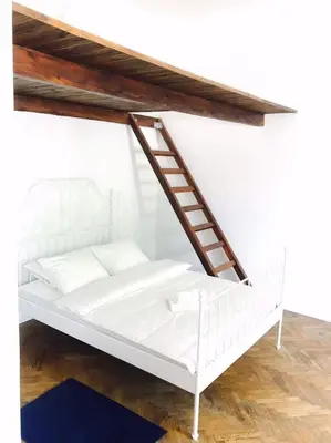 a white bed with a ladder on top of it at Przestrzenny apartament w centrum Krakowa. in Kraków