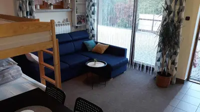 a living room with a blue couch in front of a window at Apartament Kapi in Kalwaria Zebrzydowska
