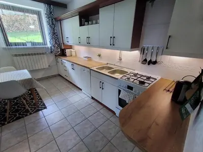 a kitchen with white cabinets and a wooden table at Apartament Kapi in Kalwaria Zebrzydowska