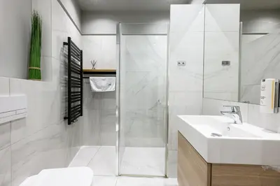 a white bathroom with a shower and a sink at Arts Apartments - Kraków Old Town in Kraków