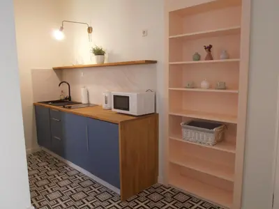 a kitchen with a counter with a microwave and shelves at Apartamenty Rudi in Kraków
