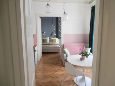 a living room with a table and a pink couch at Apartamenty Rudi in Kraków