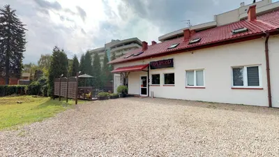 a white building with a red roof on a gravel driveway at Noclegi Czarna Perła in Kraków