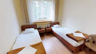 two beds in a small room with a window at Noclegi Czarna Perła in Kraków