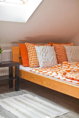 a bed with orange and white pillows on it at Hostel 33 in Trzebinia