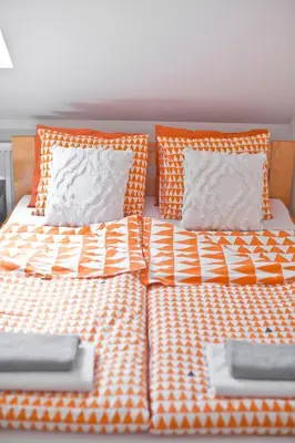 a bed with orange and white sheets and pillows at Hostel 33 in Trzebinia