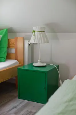a green nightstand with a lamp on it next to a bed at Hostel 33 in Trzebinia