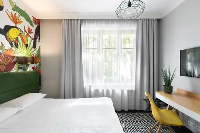 a hotel room with a bed and a desk and a window at Liv'Inn Aparthotel in Kraków