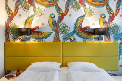 a bedroom with a yellow headboard and a colorful wall at Liv'Inn Aparthotel in Kraków