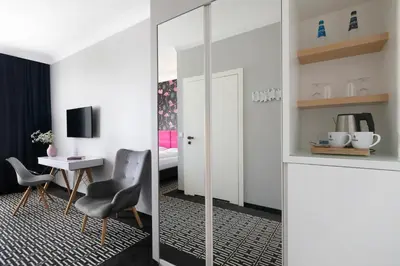 a room with a table and two chairs and a mirror at Liv'Inn Aparthotel in Kraków