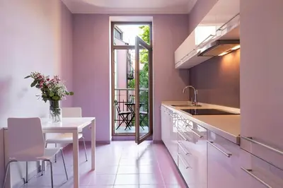 a kitchen with pink walls and a table with a vase of flowers at Liv'Inn Aparthotel in Kraków