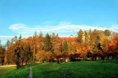 a green field with trees and a building in the background at Dom Gości Opactwa Benedyktynów in Tyniec