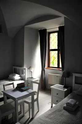 a bedroom with two beds and a table and a window at Dom Gości Opactwa Benedyktynów in Tyniec