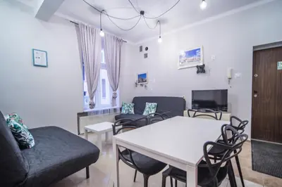 a living room with a couch and a table and chairs at Apartament Izaaka in Kraków
