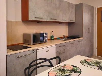 a kitchen with a microwave and a table with chairs at Apartament Izaaka in Kraków