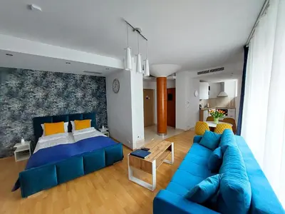 a living room with a blue couch and a bed at NOOK NOOK Apartments Kazimierza Wielkiego 104 in Kraków