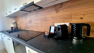 a kitchen with a black counter top and wooden wall at NOOK NOOK Apartments Kazimierza Wielkiego 104 in Kraków