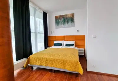 a bedroom with a bed with a yellow bedspread at NOOK NOOK Apartments Kazimierza Wielkiego 104 in Kraków