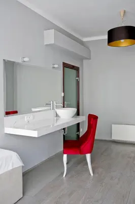 a bathroom with a sink and a red chair at Elegant City Center Zyblikiewicza 165 in Kraków