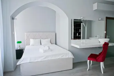 a bedroom with a white bed with a sink and a red chair at Elegant City Center Zyblikiewicza 165 in Kraków