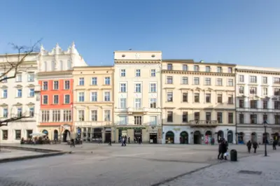 a bedroom with a large bed and a table and a kitchen at Venetian House Market Square Aparthotel in Kraków