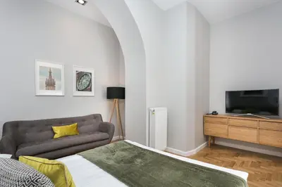 a bedroom with a bed and a tv on a wall at Venetian House Market Square Aparthotel in Kraków