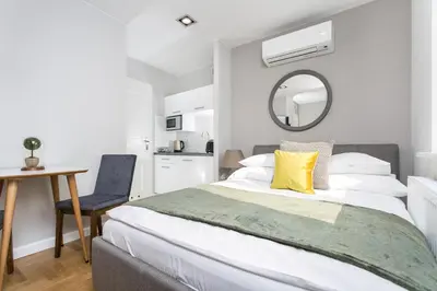 a bedroom with a bed and a desk and a table at Venetian House Market Square Aparthotel in Kraków