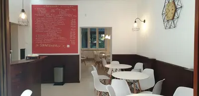 a restaurant with tables and white chairs and a red sign at Finger Guest Rooms in Kraków
