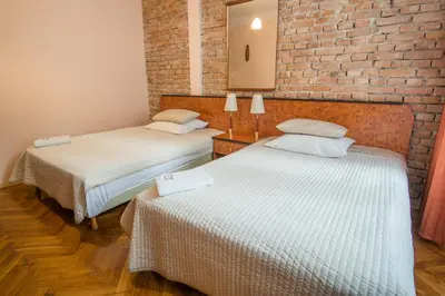 two beds in a room with a brick wall at Finger Guest Rooms in Kraków