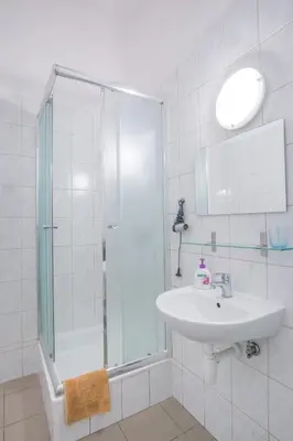 a white bathroom with a sink and a shower at Finger Guest Rooms in Kraków