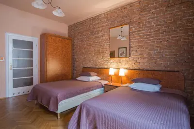 a bedroom with two beds and a brick wall at Finger Guest Rooms in Kraków