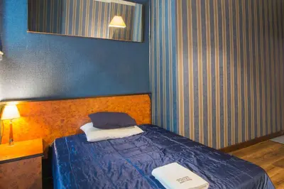 a small bedroom with a bed with a blue wall at Finger Guest Rooms in Kraków