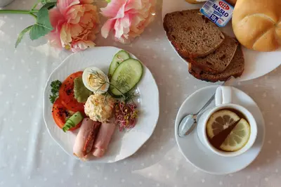 a plate of food with a hot dog and a cup of coffee at Hotel Grand Felix in Kraków