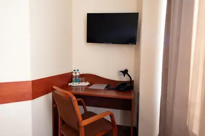 a desk with a chair and a television on a wall at Hotel Grand Felix in Kraków