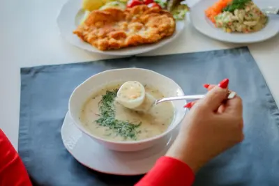 a child eating a bowl of soup with a spoon at Hotel Grand Felix in Kraków