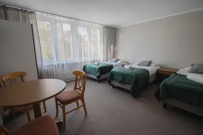 a room with two beds and a table and chairs at Hotel Felix in Kraków