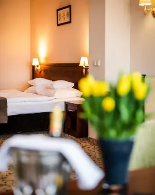 a hotel room with a bed and a vase of flowers at Dosłońce Resort Wellness & Farm in Racławice