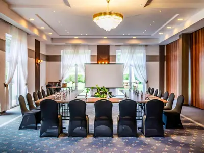 a conference room with a table and chairs and a screen at Dosłońce Resort Wellness & Farm in Racławice