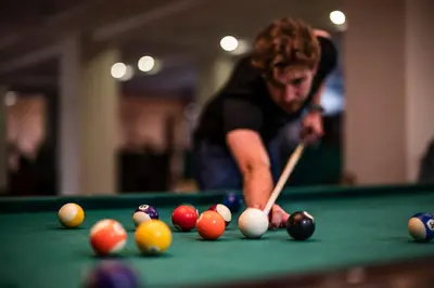 a man playing billiard with a cue on a pool table at Dosłońce Resort Wellness & Farm in Racławice