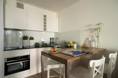 a kitchen with white cabinets and a wooden table at Belle Epoque Residence in Kraków