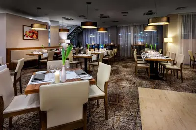 a dining room filled with tables and chairs at Hilton Garden Inn Krakow in Kraków