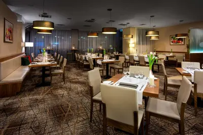 a dining room with tables and chairs and lights at Hilton Garden Inn Krakow in Kraków