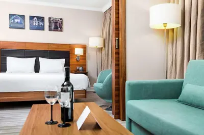 a hotel room with a bed and a bottle of wine on a table at Hilton Garden Inn Krakow in Kraków