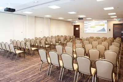 a room with rows of chairs and a projection screen at Hilton Garden Inn Krakow in Kraków
