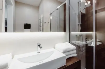 a white bathroom with a sink and a mirror at 4Seasons﻿ Apartments Cracow in Kraków